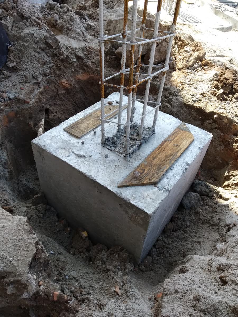 Bloco de fundação concretado com a ferragem de arranque do pilar saindo pelo topo, escorada no prumo